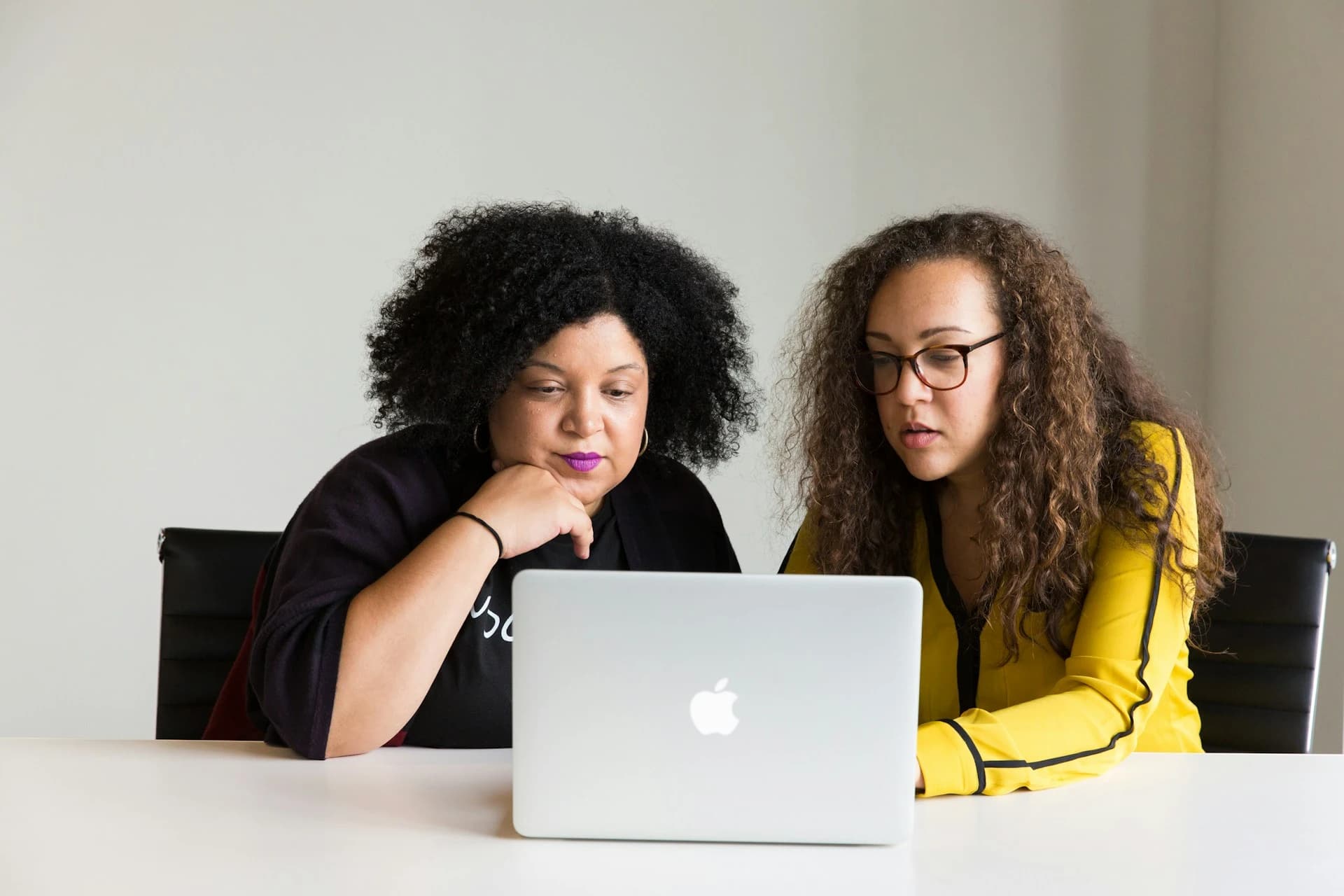 A support worker collaborating with a young person on a laptop.